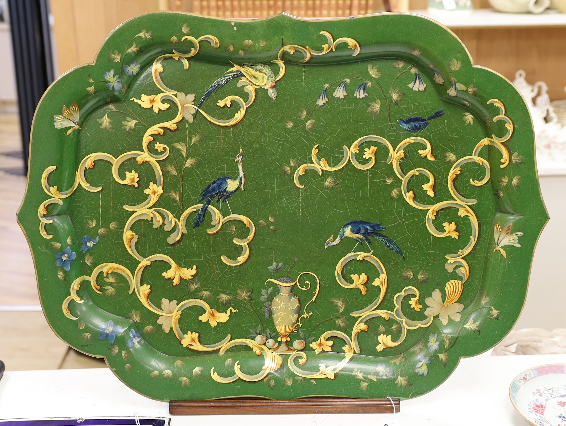 A green lacquered Papier mache tray with ornate gilding style decoration, with associated hardwood stand, 80cm wide